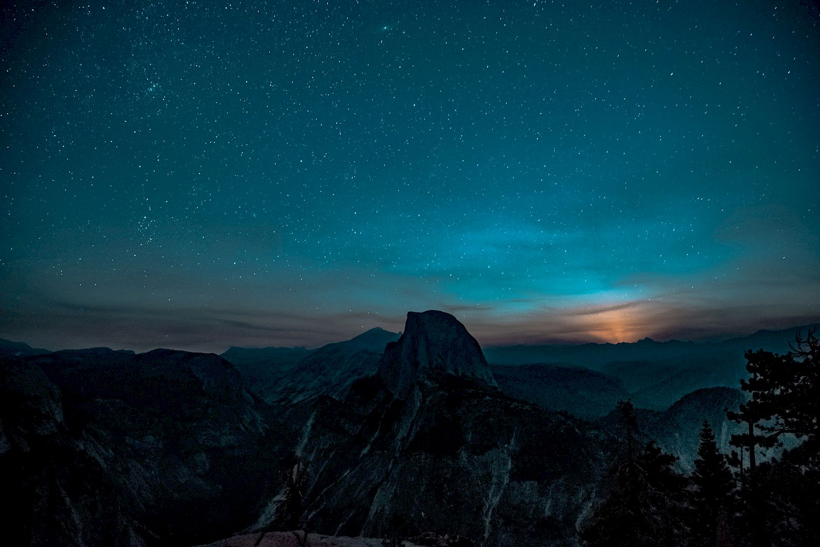 A mountain landscape under a starry night sky with a glowing horizon is shown.