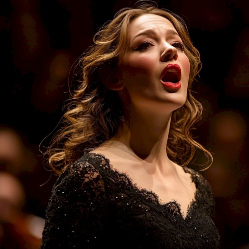 A woman in elegant attire is singing passionately on stage against a blurred background of people.